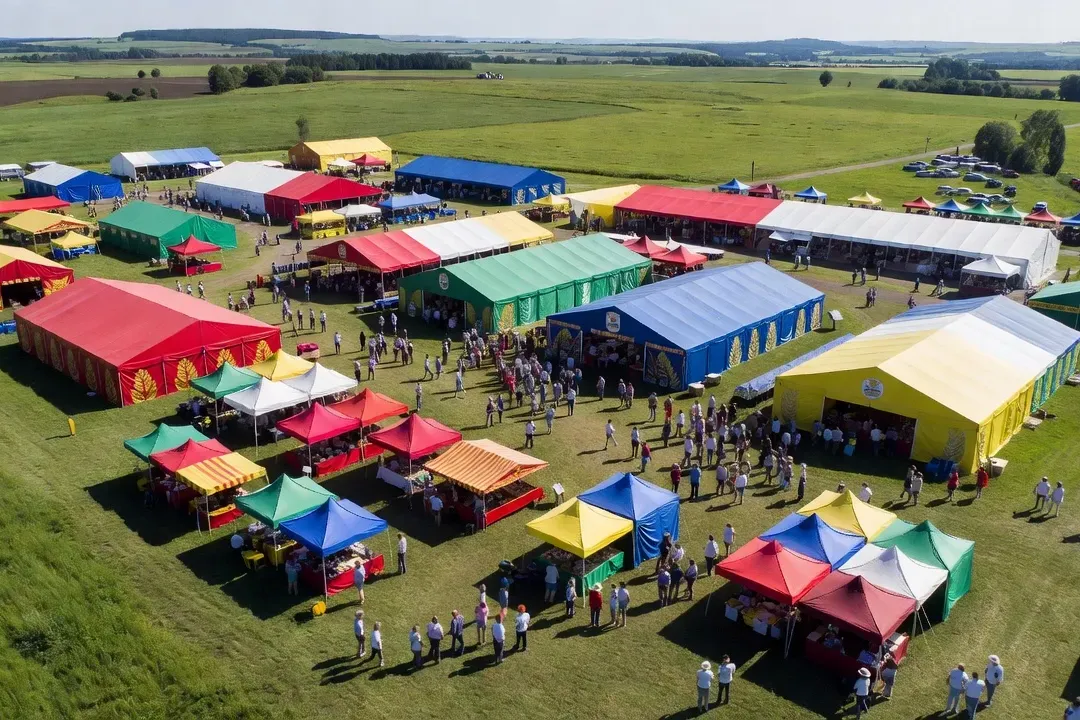 Vue aérienne d'une grande foire agricole en Europe de l'Est — pavillons colorés et visiteurs